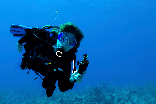 Female scuba diver looking at her dive computer in crystal blue water.a.m.