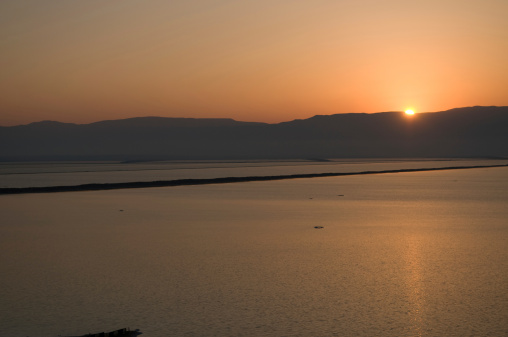 The sun rises over the mountains in Jordan as seen from the shore in Israel.