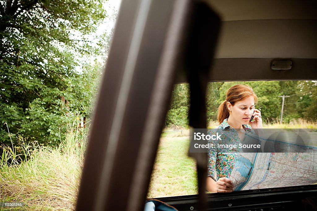 Mulher usando o celular e mapa, vistos através de um carro - Foto de stock de Mulheres royalty-free