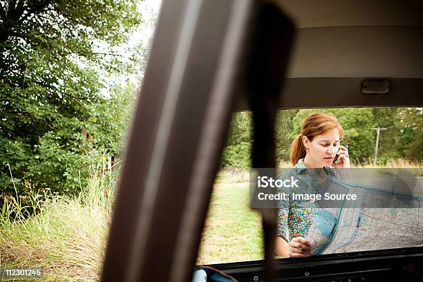 Mulher Usando Cellphone E Mapa Vista Através De Um Carro - Fotografias de stock e mais imagens de Mulheres