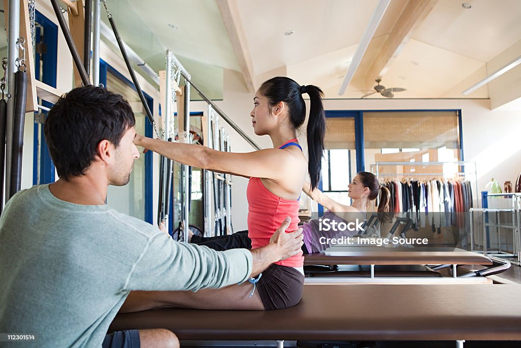 Pilates instructor assisting woman  Pilates Stock Photo