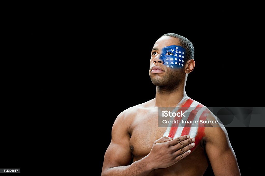 Man with US flag painted on face and shoulder, hand on chest  American Flag Stock Photo