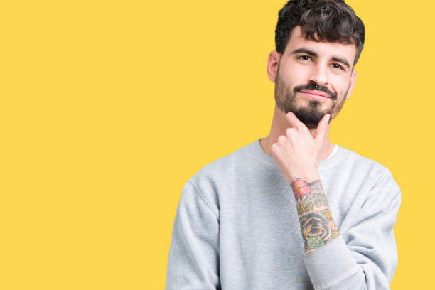 istock Young handsome man wearing sweatshirt over isolated background looking confident at the camera with smile with crossed arms and hand raised on chin. Thinking positive. 1124223655