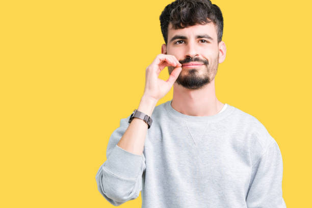 istock Young handsome man wearing sweatshirt over isolated background mouth and lips shut as zip with fingers. Secret and silent, taboo talking 1124223687