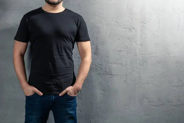 Photo of Young healthy man with black T-shirt on concrete background with copyspace for your text. Picture without model face.