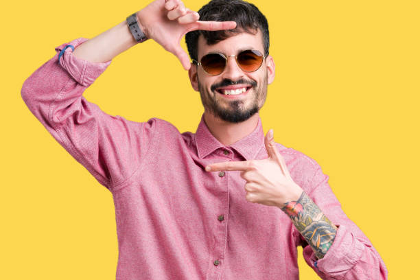 istock Young handsome man wearing sunglasses over isolated background smiling making frame with hands and fingers with happy face. Creativity and photography concept. 1124223872