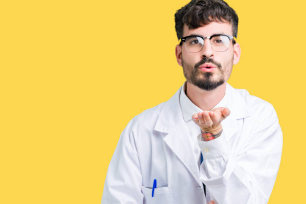 istock Young professional scientist man wearing white coat over isolated background looking at the camera blowing a kiss with hand on air being lovely. Love expression. 1124224238