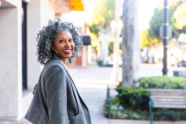 a carefree black woman looking back over her shoulder - mid aged woman imagens e fotografias de stock