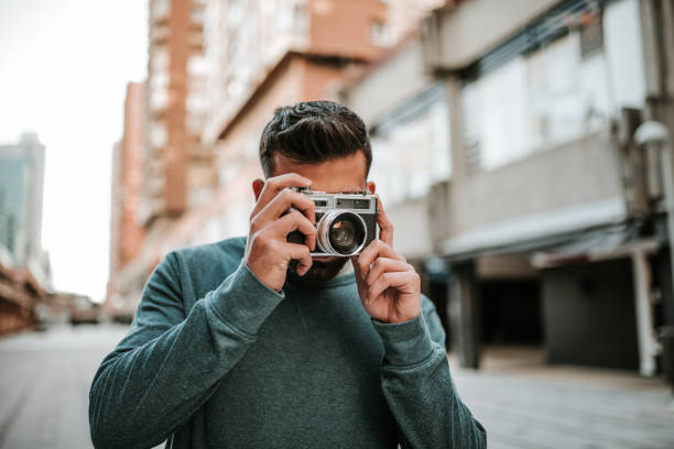 istock Young man taking a picture with a vintage camera 1124226622