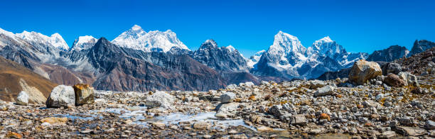 The iconic summit pyramid of Mt. Everest (8848m), Nuptse (7861m) and Lhotse (8516m) towering over the snow capped peaks and dramatic mountain pinnacles of the Himalayas high in the winter wilderness of the Sagarmatha National Park, Nepal.
