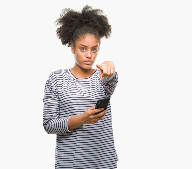 istock Young afro american woman texting using smartphone over isolated background pointing with finger to the camera and to you, hand sign, positive and confident gesture from the front 1124230498