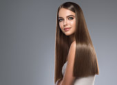 Young, brown haired beautiful model with long,  straight, well groomed hair. Hair care and hairdressing art.