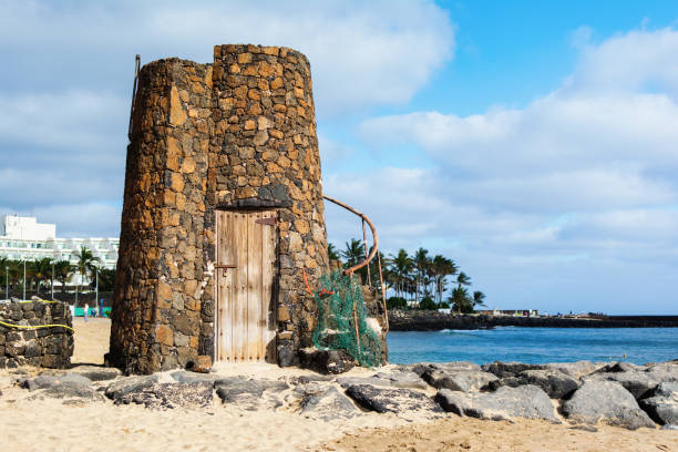 Stone tower in Las Cucharas beach, Lanzarote, Canary islands. VIew of the sea, sandy beach and rocks