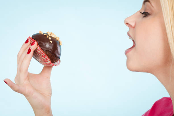 istock Woman holding chocolate cupcake about to bite 1124239052