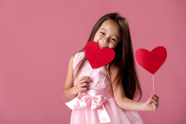 紙の心を保持しているピンクのドレスかわいい女の子 - heart shape child human hand childhood ストックフォトと画像