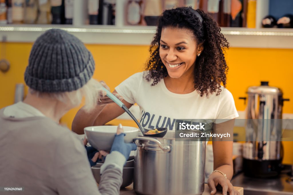 Nice friendly nice woman enjoying her job Being a volunteer. Nice friendly woman smiling while enjoying her job as a volunteer Homelessness Stock Photo