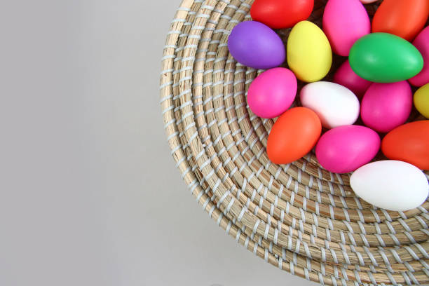 istock Brightly colored easter eggs, in a straw basket against a grey background. 1124245558