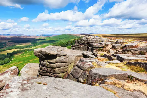 Rock formations in Stanage edge, with the fields and pastures on the background. Peak District National Park, Derbyshire, England , selective focus