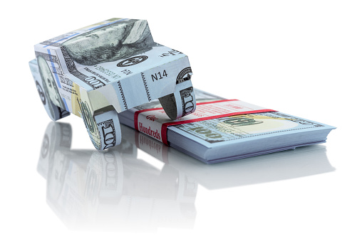 Luxury car and stack of money isolated on white. The image is a symbol of personal and financial success.