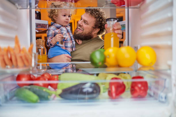 istock Father and son taking food from fridge late at night. 1124256101