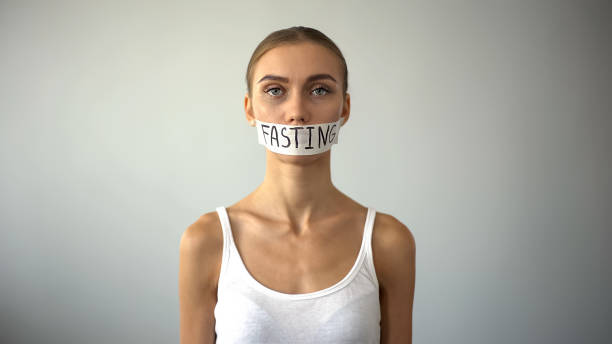 Fasting word written on taped mouth of upset anorexic model, self-destruction Fasting word written on taped mouth of upset anorexic model, self-destruction self destructive stock pictures, royalty-free photos & images