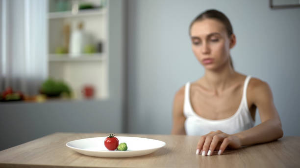 istock Exhausted slim woman looking at small portion of breakfast, self-destruction 1124272131