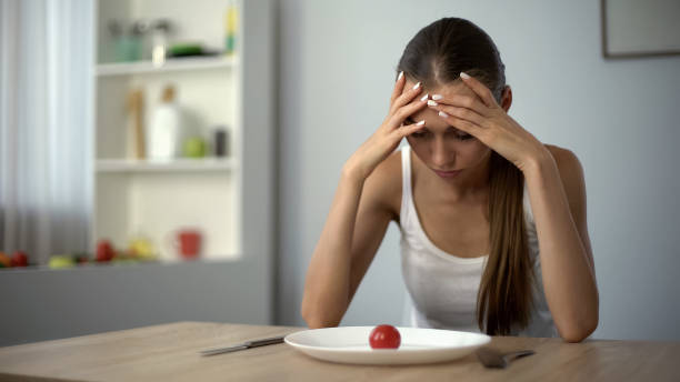 Anorexic girl feels dizzy, depleted by severe diets, exhausted body, starvation stock photo