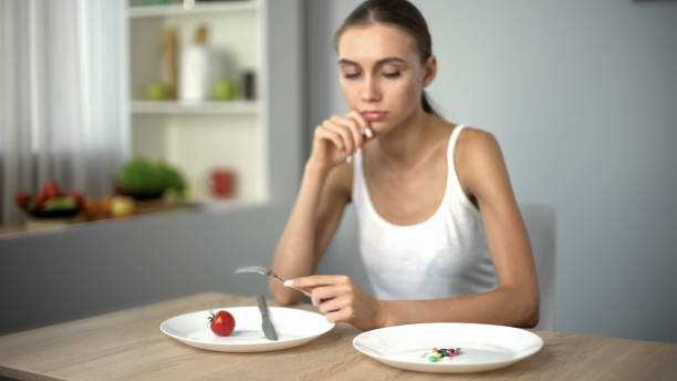 thin girl looking at anti-obesity pills, obsession with weight loss, addiction - anorexia imagens e fotografias de stock