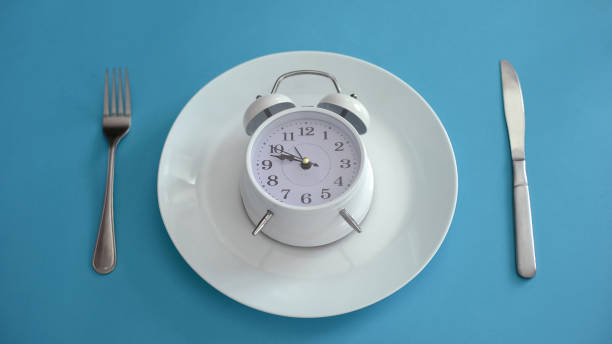 istock Alarm clock on plate, adhere to diet time, proper nutrition, discipline, closeup 1124272307