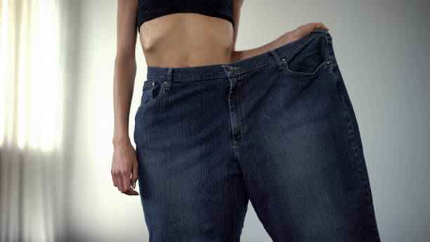 Anorexic girl wearing one trouser-leg, fat people vs skinny, rapid weight loss Anorexic girl wearing one trouser-leg, fat people vs skinny, rapid weight loss self destructive stock pictures, royalty-free photos & images