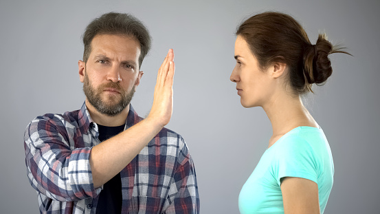 Man showing stop sign to annoyed wife who constantly screaming and complaining