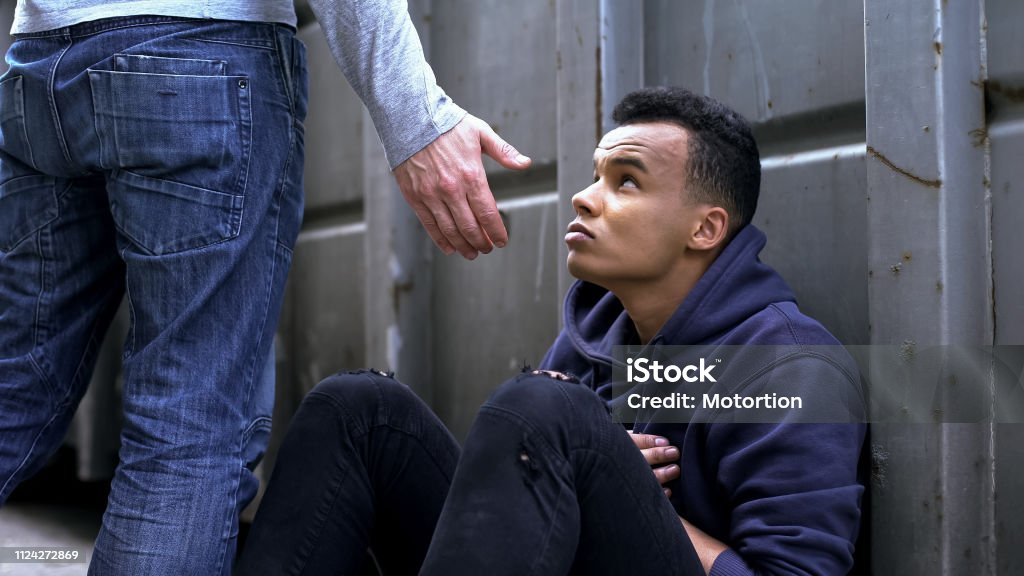 Passing by man offering helping hand to street child, kindness and charity Homelessness Stock Photo