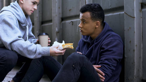 adolescentes compartiendo almuerzo con amigo afroamericano, apoyo en situación difícil - homelessness men white black fotografías e imágenes de stock