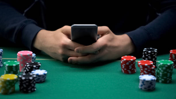 istock Male player betting on smartphone application, casino chips table, online game 1124272949