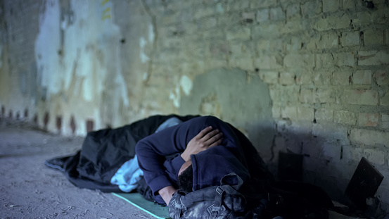 Poverty, homeless young man sleeping on street, indifferent egoistic society