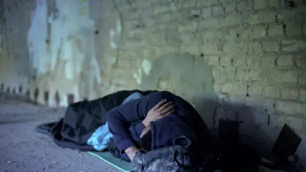 Photo of Poverty, homeless young man sleeping on street, indifferent egoistic society