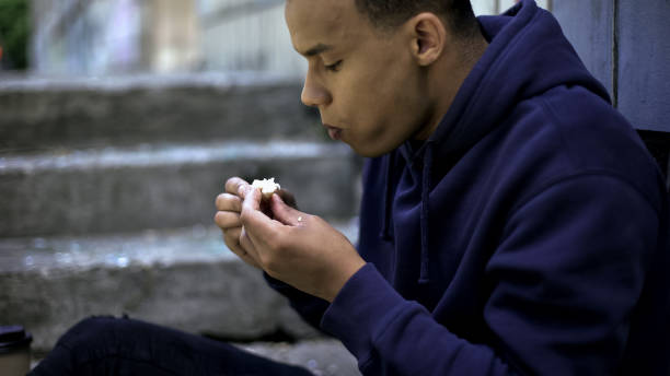 poor homeless boy eating remains of food found on street, cruel reality, poverty - eating sandwich emotional stress food imagens e fotografias de stock