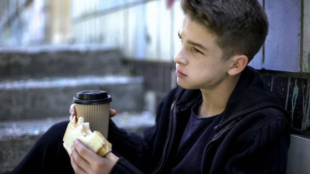 schoolboy eating lunch around school corner alone, bullying by senior students - eating sandwich emotional stress food imagens e fotografias de stock