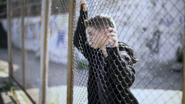 istock Caucasian boy watching rich district through fence, poverty, immigration 1124273692