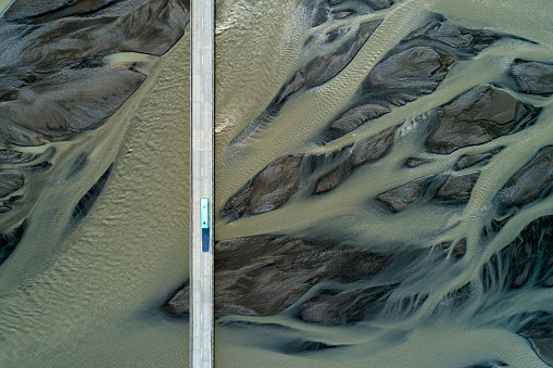 Bus driving on bridge over glacial river, aerial view, South Iceland.