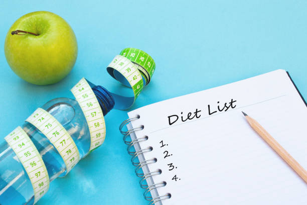 istock Fresh apple, measuring tape, water bottle and notebook on blue background. 1124283328