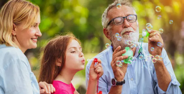 Photo of Happy family blowing soap bubbles in the park.