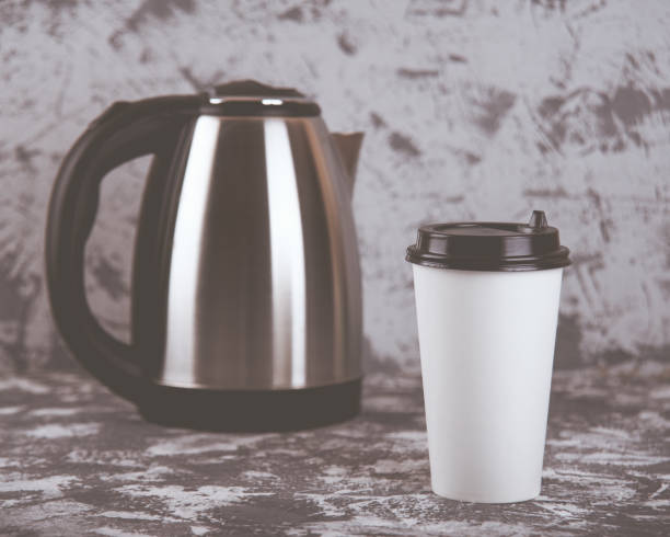istock Working on the go. Coffee cup and electric kettle on grey stone table. Copy space 1124296960