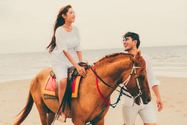 istock Young couple goes horse riding on tropical beach. 1124298122