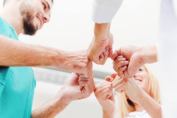 médecin, chirurgien et une infirmière joignent les mains ensemble. - general practitioner photos et images de collection