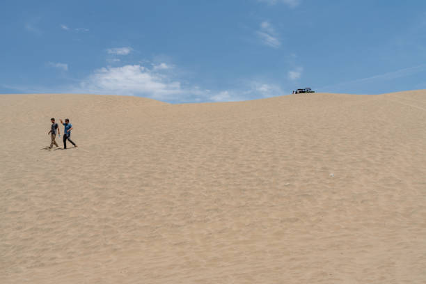 Huacachina, Peru - October 19, 2018: Dune buggy in a desert near Huacachina, Ica region, Peru. Tourists are joining the most famous tour, the sandboarding.