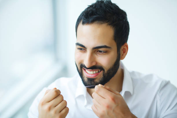 istock Teeth Care. Beautiful Smiling Man Flossing Healthy White Teeth. High Resolution Image 1124305856