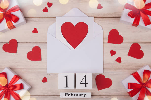 Wooden white background with red hearts, gifts, love envelope and wooden block calendar. The concept of Valentine Day. Top viev. stock photo