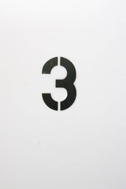 Number three stenciled in black paint on white wall