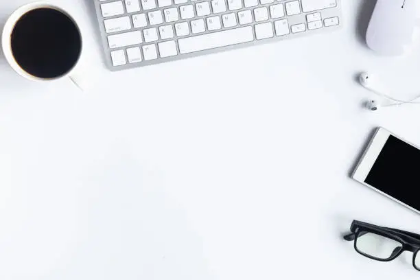 White desk office with laptop, smartphone and other supplies with cup of coffee. Top view with copy space for input the text. Designer workspace on desk top, view with essential elements on flat lay.